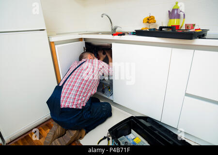 Le riparazioni del lavoratore il problema di perdita nel lavello da cucina Foto Stock