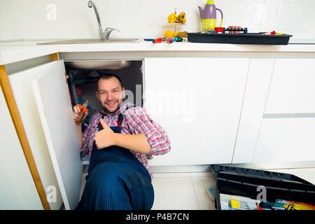 Le riparazioni del lavoratore il problema di perdita nel lavello da cucina Foto Stock