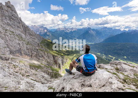 L'Europa, Italia, Veneto, Agordino, alpinista osserva il panorama alla fine della ferrata Stella Alpina sul Monte Agner e delle Pale di San Martino e Dolomiti Foto Stock