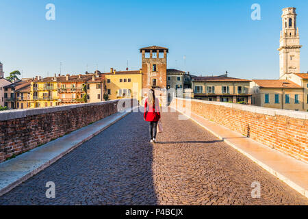 Donna che cammina lungo il Ponte Pietra (ponte di pietra). Verona, Veneto, Italia Foto Stock