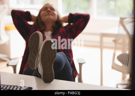 Stanco di sesso femminile rilassante executive con i piedi sul tavolo Foto Stock
