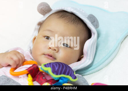 Close up Asian carino new born baby giocattoli di riproduzione sul letto bianco. Foto Stock