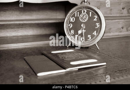 Blu di passaporto britannico e il passaporto australiano con il vecchio orologio sveglia su legni antichi scrivania in seppia Foto Stock