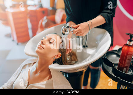 Parrucchiere lavaggi dei capelli del cliente nel bacino Foto Stock