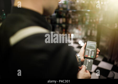 Stretta di mano con carta di credito passando il dito verso la macchina a pagare. Foto Stock