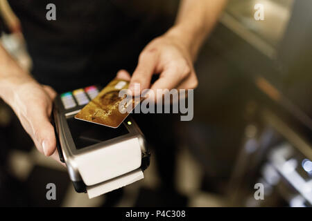 Mano del cliente di pagare con credito contactless card con te NFC Foto Stock