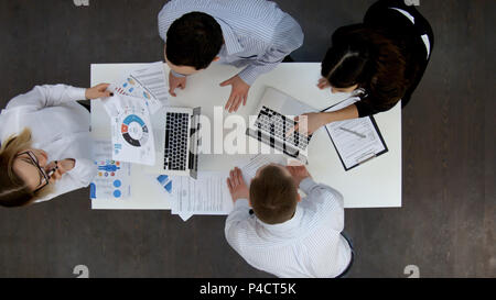 Ofice lavoratori discutere di affari diagrammi e wokring sui notebook Foto Stock