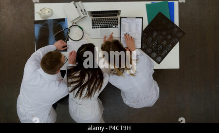 Tre medici concentrato utilizzando computer portatile in ufficio Foto Stock