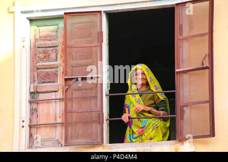 Donna locale guardando fuori della finestra a Jaipur, Rajasthan, India. Jaipur è la capitale e la città più grande del Rajasthan. Foto Stock