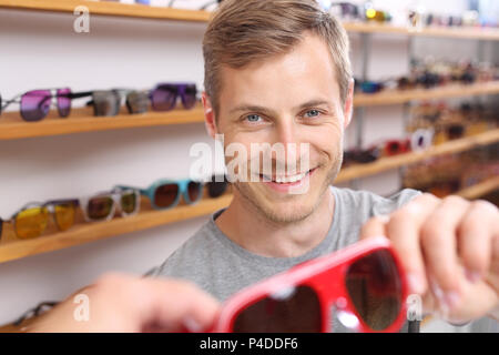 Occhiali da sole. L'uomo sta cercando sui bicchieri. Foto Stock