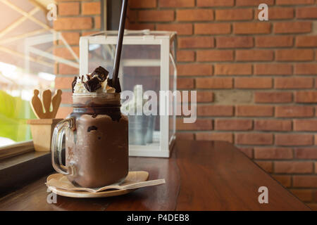 Dark Chocolate milk shake con panna montata brownie sulla tavola di legno, nella finestra di sfondo cafe, bevande in estate. Foto Stock