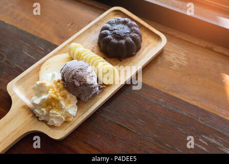 Cioccolato torta di lava impostato con cioccolato gelato banana apple la frutta e la panna montata su tavola di legno in cafe, dolce estate. Foto Stock