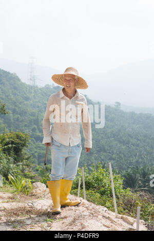 Lavoratore in Asia terra di pulizia sotto il sole caldo. Foto Stock