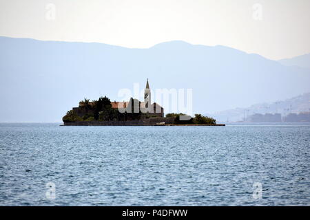 Lonely isola in mezzo al mare contro lo sfondo delle montagne Foto Stock