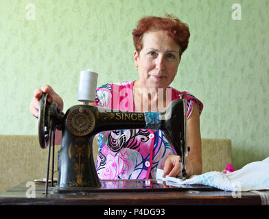 Jartsevo, Russia - Luglio 28, 2014: Una donna anziana cuce su una vecchia macchina da cucire Foto Stock