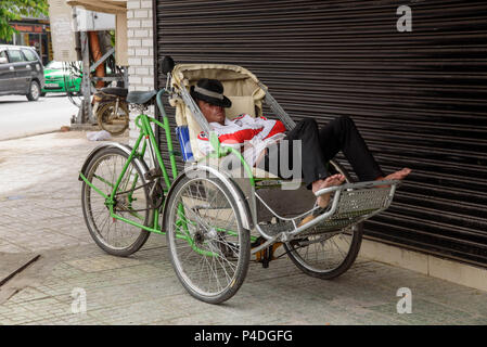 Il Vietnam, Nha Trang - Gennaio 3, 2016: driver Rickshaw dorme sulla sua bicicletta in strada a lavorare mentre si è in attesa per i clienti Foto Stock