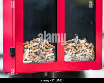 Scartato mozziconi di sigaretta in un pavimento trasparente bin Foto Stock