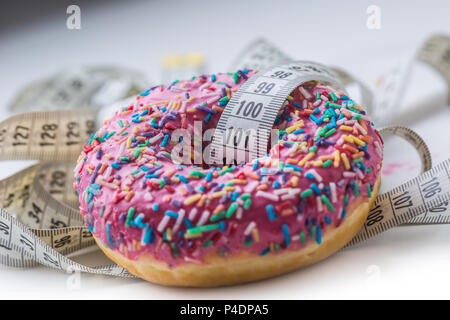 Close-up smerigliato rosa ciambella con bianco misura su misura nastro. Foto Stock