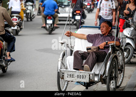 Hanoi, Vietnam - Marzo 15, 2018: Rickshaw driver e di riposo in attesa di clienti nella città vecchia di Hanoi e Foto Stock