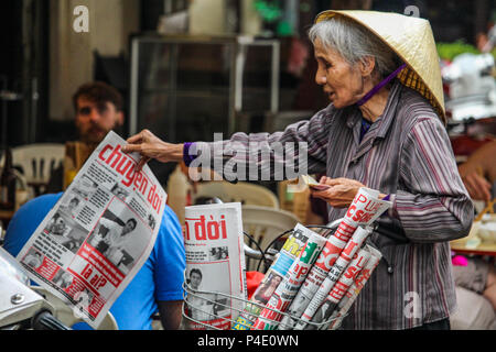 Hanoi, Vietnam - Marzo 15, 2018: Senior lady vendita di quotidiani locali con una bicicletta Foto Stock