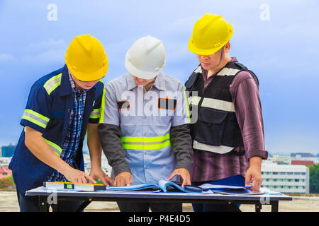 Costruzione gli ingegneri che lavorano insieme guardando il blueprint al sito in costruzione, buona per il lavoro di squadra e tema di ingegneria Foto Stock