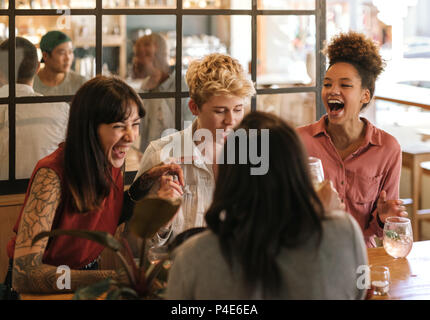 Variegato gruppo di amiche ridere insieme in un bar alla moda Foto Stock