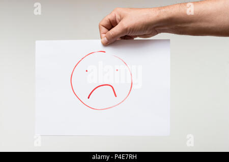 Un foglio di carta con un disegno di un volto triste Foto Stock
