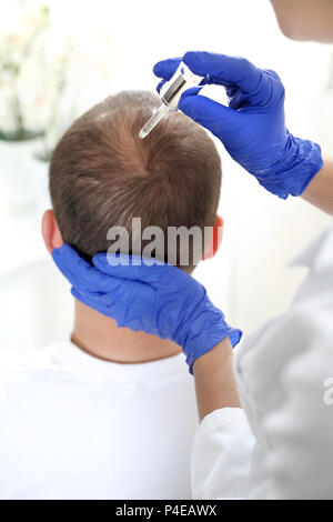 Ampolla per la crescita dei capelli. Il parrucchiere mette la preparazione sui capelli dell'uomo. Fiala per capelli. Nutrizione del cuoio capelluto applicando i preperati cosmetici. Foto Stock