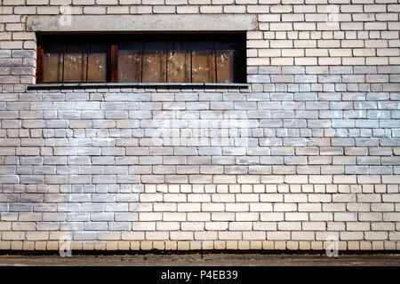 Bianco parete in mattoni con una finestra imbarcato, strutture edili, edificio abbandonato, finestra con shot marks Foto Stock