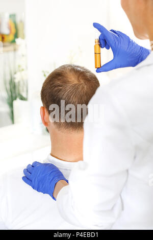 Ampolla per la crescita dei capelli. Il parrucchiere mette la preparazione sui capelli dell'uomo. Fiala per capelli. Nutrizione del cuoio capelluto applicando i preperati cosmetici. Foto Stock