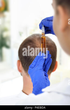 Ampolla per la crescita dei capelli. Il parrucchiere mette la preparazione sui capelli dell'uomo. Fiala per capelli. Nutrizione del cuoio capelluto applicando i preperati cosmetici. Foto Stock