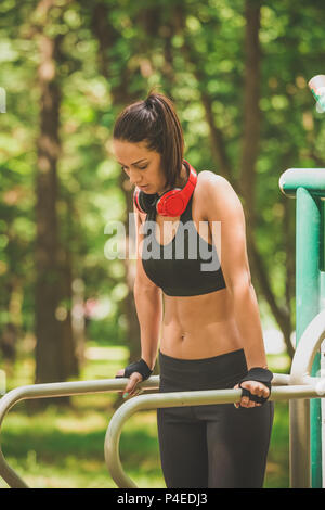 Sportive facendo tricipiti dips su barre parallele in natura. Foto Stock