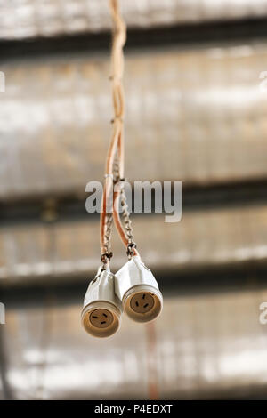 Una coppia della presa di alimentazione a 3 pin del cavo a filo del cavo appeso ad un soffitto di fabbrica del tetto. alimentazione. i cablaggi elettrici in un workshop. Foto Stock