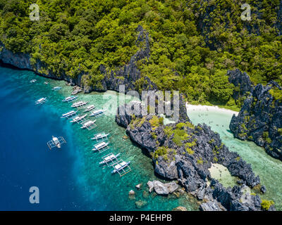 Antenna fuco vista di un gran numero di imbarcazioni turistiche accanto a una laguna tropicale e la spiaggia di El Nido, Palawan Foto Stock