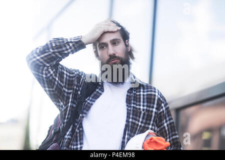 Uomo in piedi in strada con la sua mano sulla sua testa Foto Stock