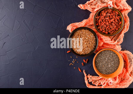 Super Foods - chia semi, semi di lino e bacche di goji in tre tazze di ceramica Foto Stock