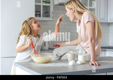 Felice madre e figlia di giocare durante la cottura insieme per la prima colazione Foto Stock