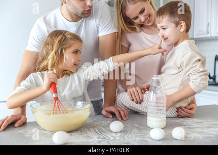 Bella famiglia giocare durante la cottura insieme per la prima colazione Foto Stock