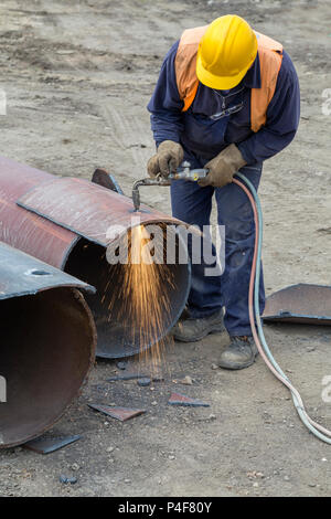 Saldatore lavoratore con cannello da taglio, foro di taglio in un tubo in acciaio. Ossigeno-propano cannello da taglio, utilizzato per il taglio di un tubo in acciaio. Foto Stock