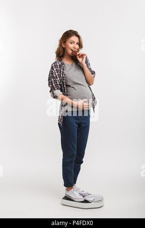 Felice donna incinta mangiando cioccolato mentre in piedi su scale Foto Stock