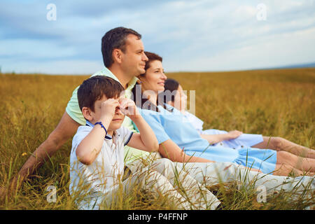 Famiglia insieme di riposo seduto su erba in natura. Foto Stock