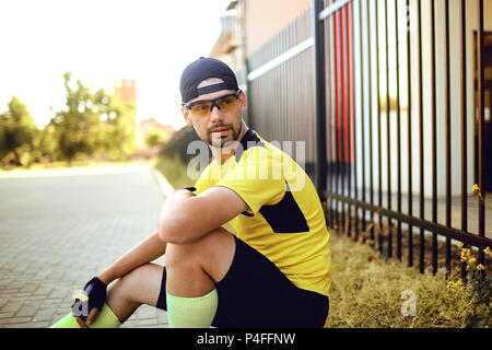 Un uomo in sportswear si siede sulla strada durante l. Foto Stock