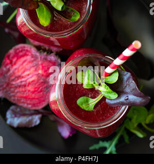 La barbabietola rossa fresca smoothie, barbabietole, rucola e le foglie di lattuga sul legno scuro dello sfondo Foto Stock