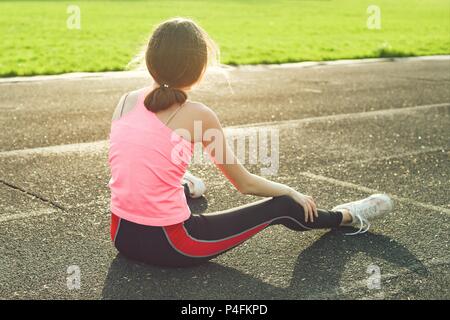 Bella ragazza adolescente riposo dopo allenamento allo stadio, ragazza sedette per rilassarsi Foto Stock