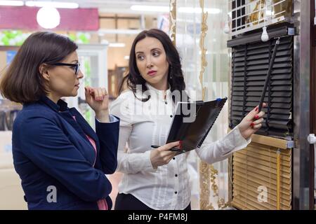 Show room di tessuti interni accessori per la decorazione della finestra. Venditore femmina mostra tessuti per tende, persiane Foto Stock
