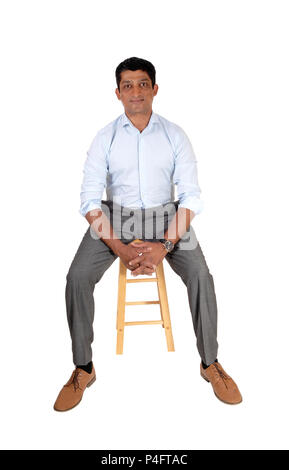 Una buona ricerca East Indian uomo in un abito pantalone e luce maglietta blu seduta su una poltrona, isolato per sfondo bianco Foto Stock