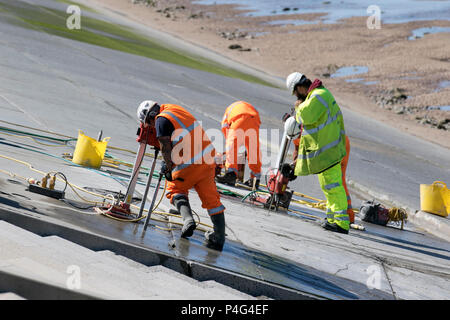 Thornton Cleveleys Lancashire, Regno Unito. Il 22 giugno 2018. Un cielo azzurro e sole sulla costa di Fylde come operai da Balfour Beatty eseguire seawall riparazioni per le difese costiere di riflessione d'onda parete. Tecnici e ingegneri provenienti da una società di costruzioni accusato dai consiglieri locali di botching quattro anni di regime in Blackpool e a quale costo £27.1m, dopo giochi formati tra le sezioni di calcestruzzo parete del mare a causa di danni causati dall'acqua e pannelli che mostrano segni di erosione. Balfour Beatty si è detto consapevole di perdita di acqua da una giunzione fra sezioni di cemento verso la parte nord del proiettore Anchorsholme difesa. Foto Stock