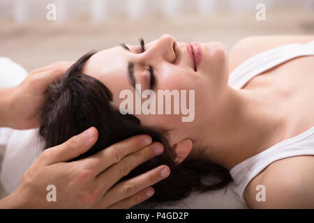 Rilassata giovane donna ricevere massaggio della testa dal terapista Foto Stock