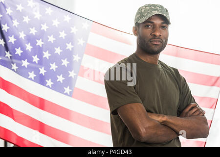 Bello african soldato americano in camuffamento vestiti di fronte a noi la bandiera Foto Stock