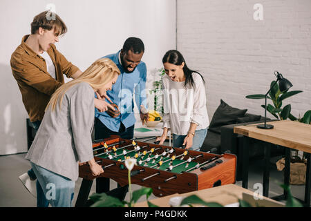 Imprenditrici a giocare il calcio balilla e due colleghi di sesso maschile puntando sul gioco di bordo Foto Stock